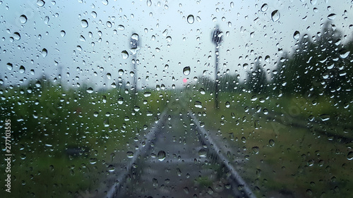 Raindrops on a window with a blurred railway road background.