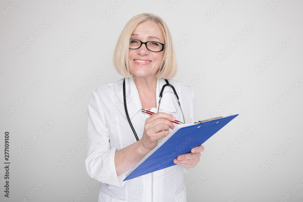 Adult female doctor in glasses smiling and writing on document isolated