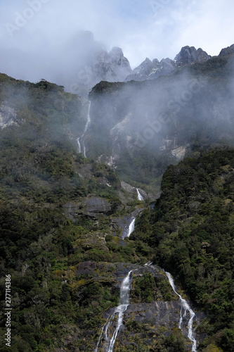 In Milford Sound cruise  one experience the spray of a waterfall close to sheer rock faces. A popular tourist destination and natural landscape in New Zealand. This view is breathtaking and iconic.