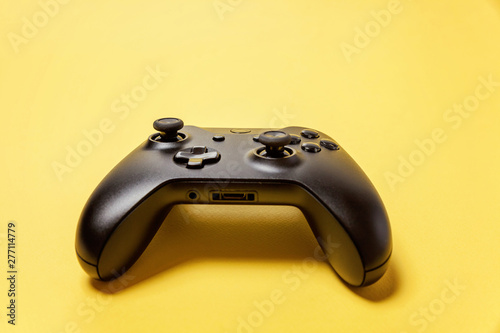 Black joystick gamepad  game console on yellow colourful trendy modern fashion pin-up background. Computer gaming competition videogame control confrontation concept. Cyberspace symbol