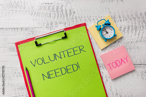 Handwriting text Volunteer Needed. Conceptual photo need work for organization without being paid Metal clipboard sheets marker alarm clock notes pad wooden background