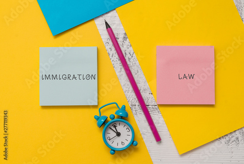 Text sign showing Immigration Law. Business photo text Emigration of a citizen shall be lawful in making of travel Notepads marker pen colored paper sheets alarm clock wooden background photo