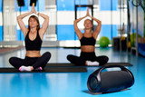 Black modern music boombox on a blurred background two young women in the gym.