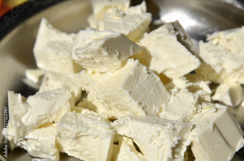 Sour milk cheese is cut into pieces lying on a platter.