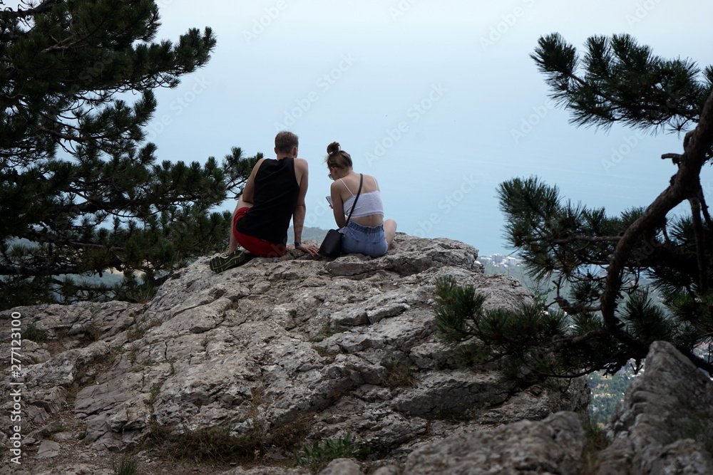 boy and girl on a big rock in a mountain forest