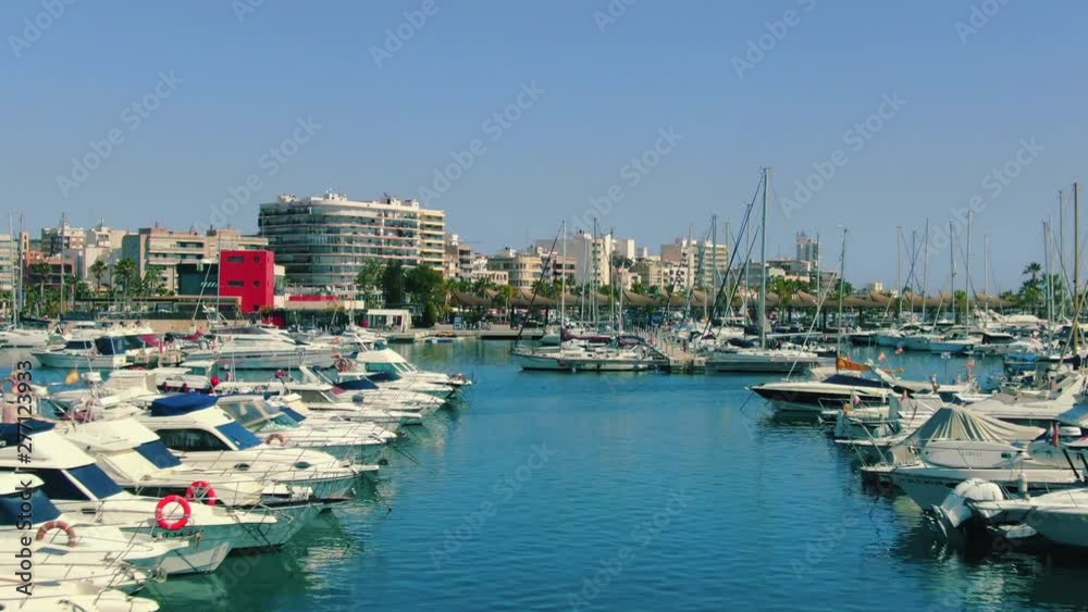 Flying through rows of nautical vessels in marina, motor boats, yachts and sailing boats moored in harbor, aerial forward dolly shot