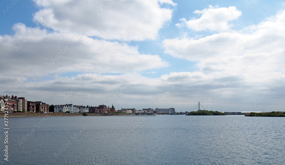 a wide panoramic view of the town of southport in merseyside from the sea with buildings along the waterfront and the bridge and pier in the distance