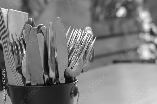 Cutlery & napkins in bucket on table. Black and white with narrow depth of field.