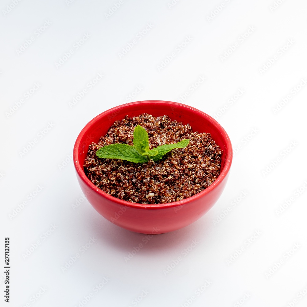 Red quinoa cooked in red bowl on white background