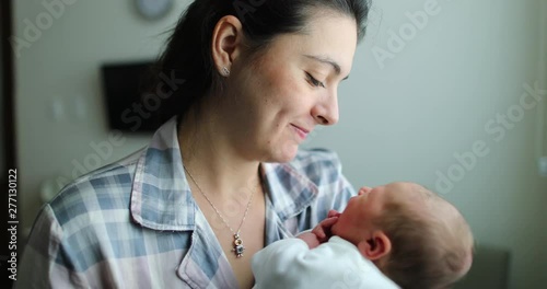 Mother holding newborn baby kissing infant, showing love after birth