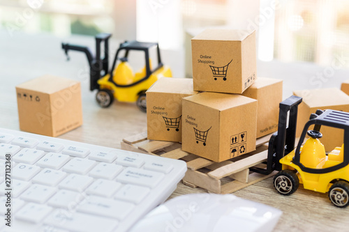 Mini forklift truck load cardboard boxes with text online shopping and symbol on wood pallet and keyboard nearby. Logistics and transportation management ideas and Industry business commercial concept