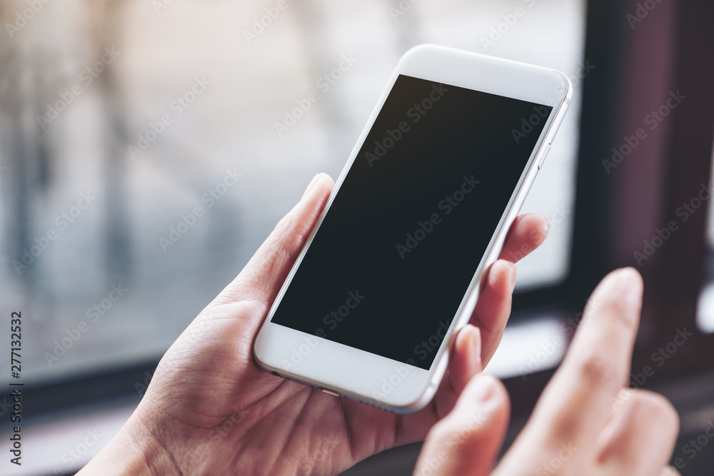 Mockup image of a woman holding white mobile phone with blank desktop screen in cafe Mockup image of a woman holding white mobile phone with blank desktop screen in cafe