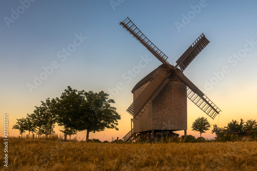 wooden windmill on a summer field during sunset