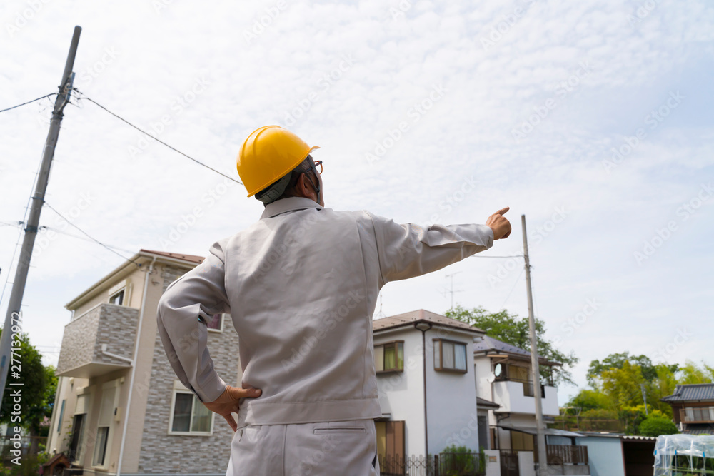 新興住宅街に立つヘルメットの男性　宅地開発　現地調査　指差し