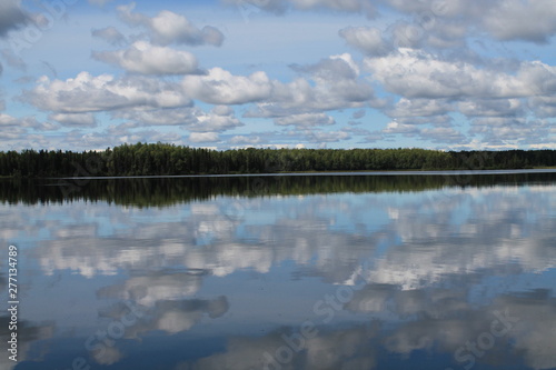 Fototapeta Naklejka Na Ścianę i Meble -  Blue sky w scattered cumulus clouds reflecting on a still tree-lined Vera Lake Alaska