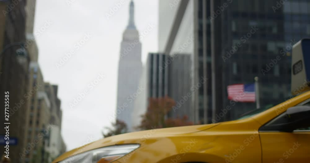 Close Up Of Iconic New York Yellow Cab With The Famous Empire State Building With Waving American flag In Beautiful Manhattan New York Close Up Of Iconic New York Yellow Cab With The Famous Empire State Building With Waving American flag In Beautiful Manhattan New York