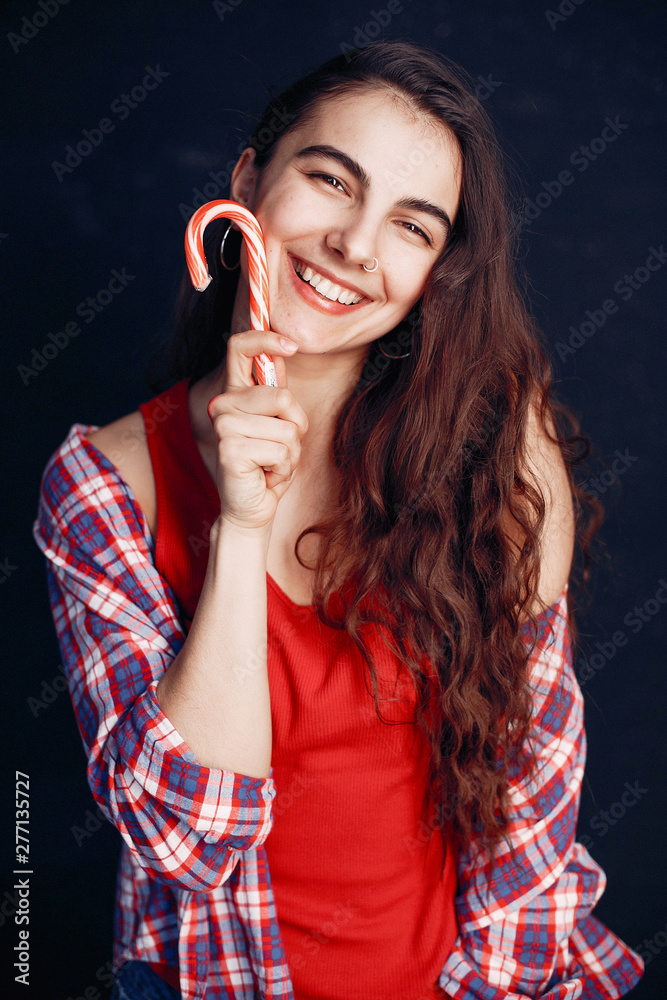 Obraz premium Beautiful girl in a room. Stylish girl in a red shirt. Lady with a candy