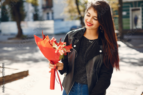 Beautiful girl in a city. Stylish girl in a fashionable clothes. Lady with a unordinary bouquet photo