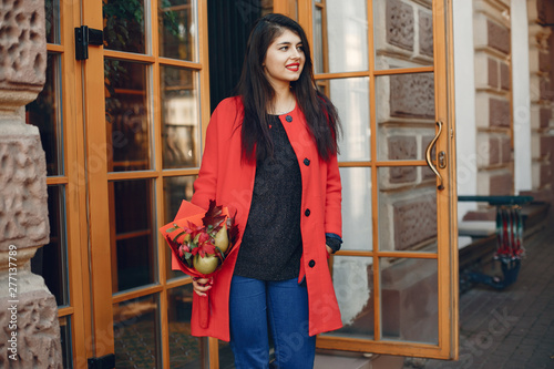 Beautiful girl in a city. Stylish girl in a fashionable clothes. Lady with a unordinary bouquet photo