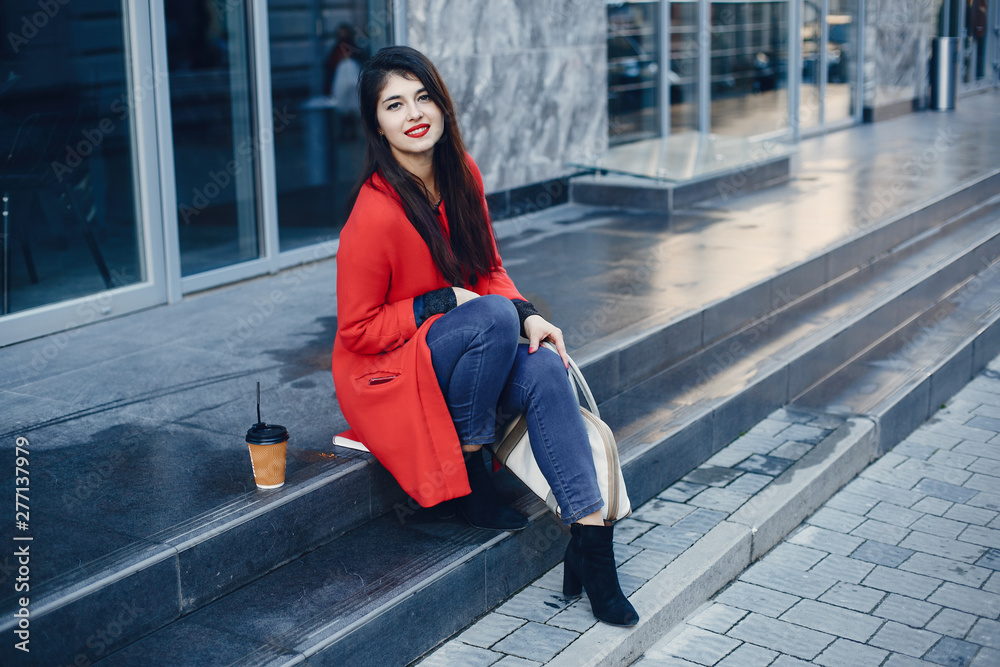 Fototapeta premium Beautiful girl in a city. Stylish girl in a fashionable clothes. Lady standing near gray building.