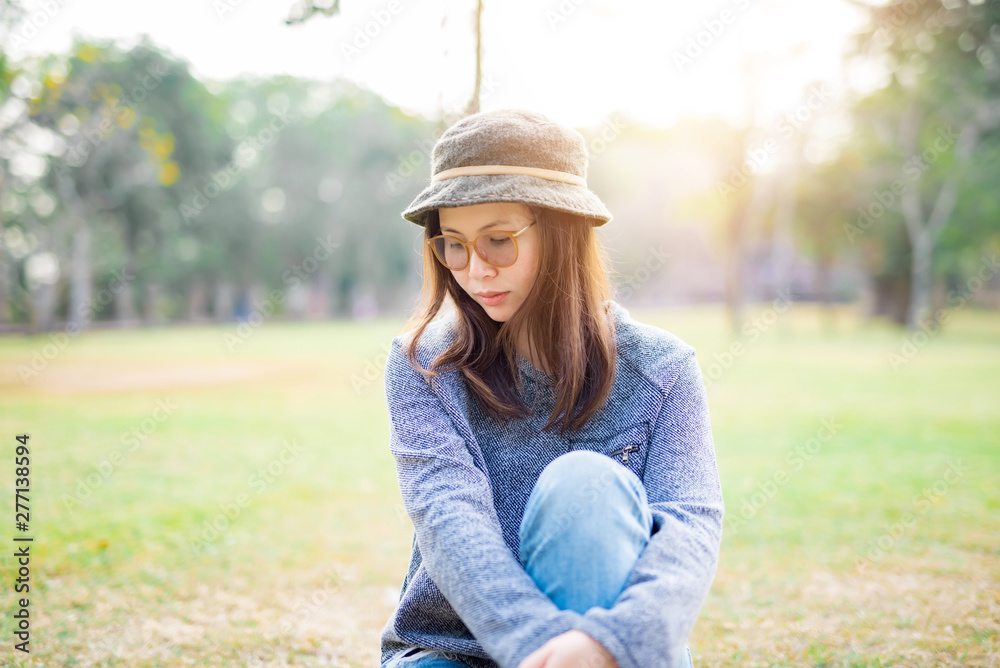 Sad woman sit down in field with sunlight background.