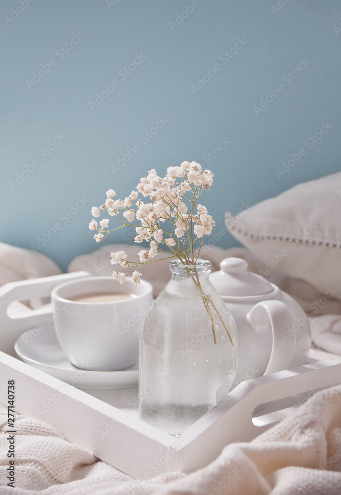 Close up of cup of tea, milk, teapot and bouquet of white flowers on the white tray. Close up of cup of tea, milk, teapot and bouquet of white flowers on the white tray.
