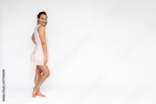 Portrait in full growth on a white background beautiful pretty girl woman in a pink dress, is facing the camera in different poses with different emotions. Smiles Stylish trendy youth.