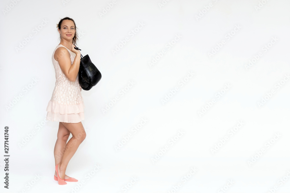 Portrait in full growth on a white background beautiful pretty woman girl in a pink dress, standing with boxing gloves in different poses with different emotions. Smiles Stylish trendy youth.