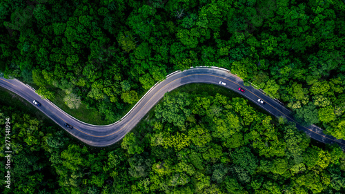 Forest Road view from above, Aerial view asphalt road in tropical tree forest with a road going through with car, Adventure in Asia background concept.