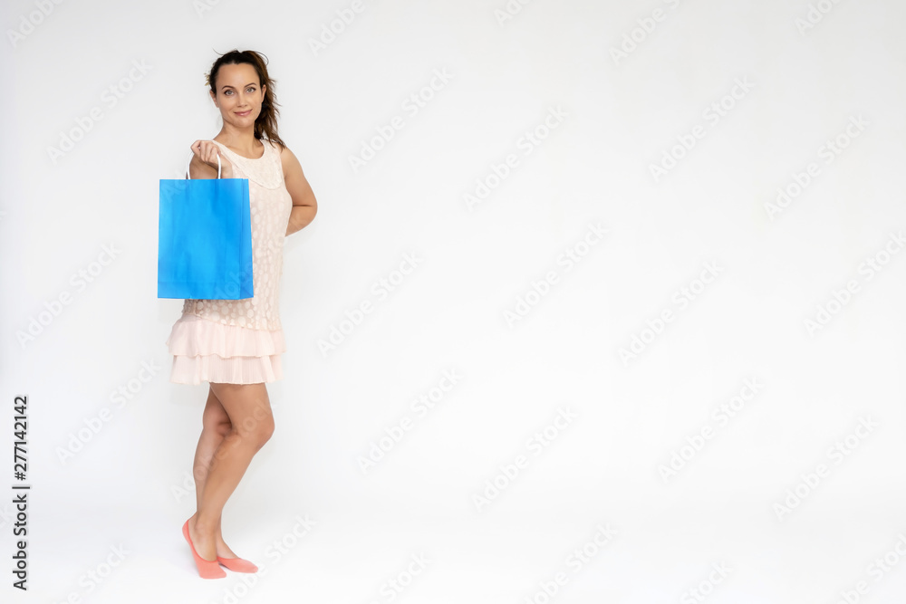 Full-length portrait on white background of a beautiful pretty woman girl in a pink dress, stands with purchases with packages in different poses with different emotions. Smiles Stylish trendy youth. Full-length portrait on white background of a beautiful pretty woman girl in a pink dress, stands with purchases with packages in different poses with different emotions. Smiles Stylish trendy youth.