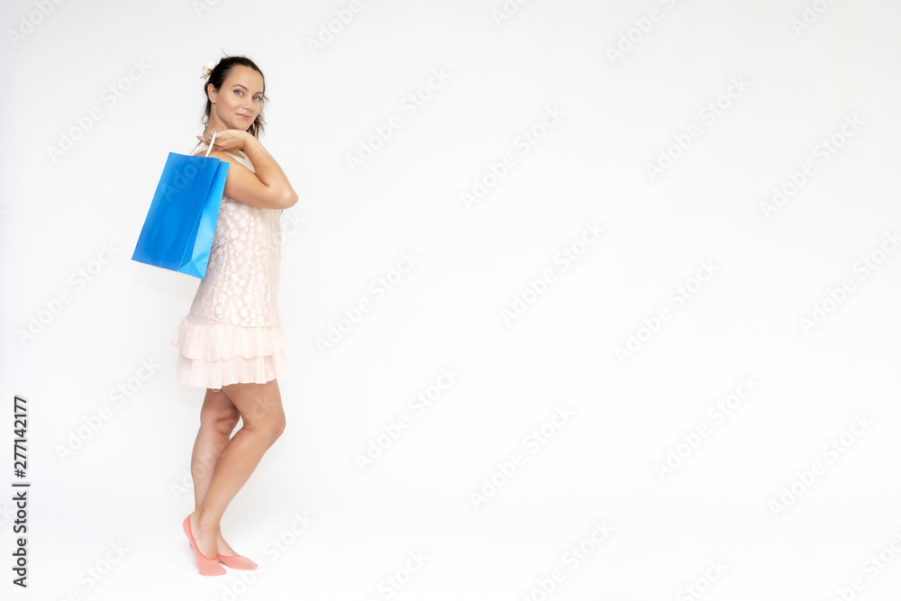 Full-length portrait on white background of a beautiful pretty woman girl in a pink dress, stands with purchases with packages in different poses with different emotions. Smiles Stylish trendy youth. Full-length portrait on white background of a beautiful pretty woman girl in a pink dress, stands with purchases with packages in different poses with different emotions. Smiles Stylish trendy youth.