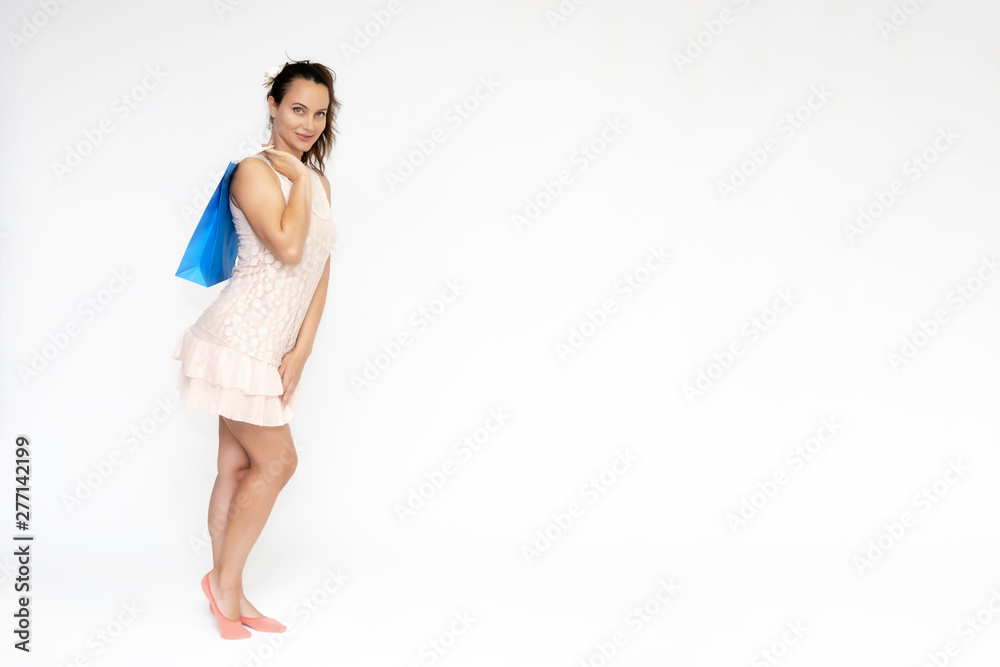 Full-length portrait on white background of a beautiful pretty woman girl in a pink dress, stands with purchases with packages in different poses with different emotions. Smiles Stylish trendy youth. Full-length portrait on white background of a beautiful pretty woman girl in a pink dress, stands with purchases with packages in different poses with different emotions. Smiles Stylish trendy youth.