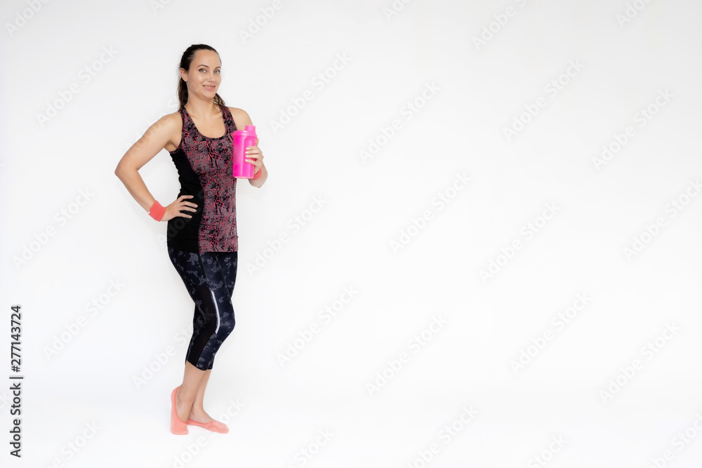 Full-length portrait on white background of beautiful pretty fitness girl woman in pink sports uniform, stands exercising in various poses with a shaker. Smiles Stylish trendy youth. Full-length portrait on white background of beautiful pretty fitness girl woman in pink sports uniform, stands exercising in various poses with a shaker. Smiles Stylish trendy youth.