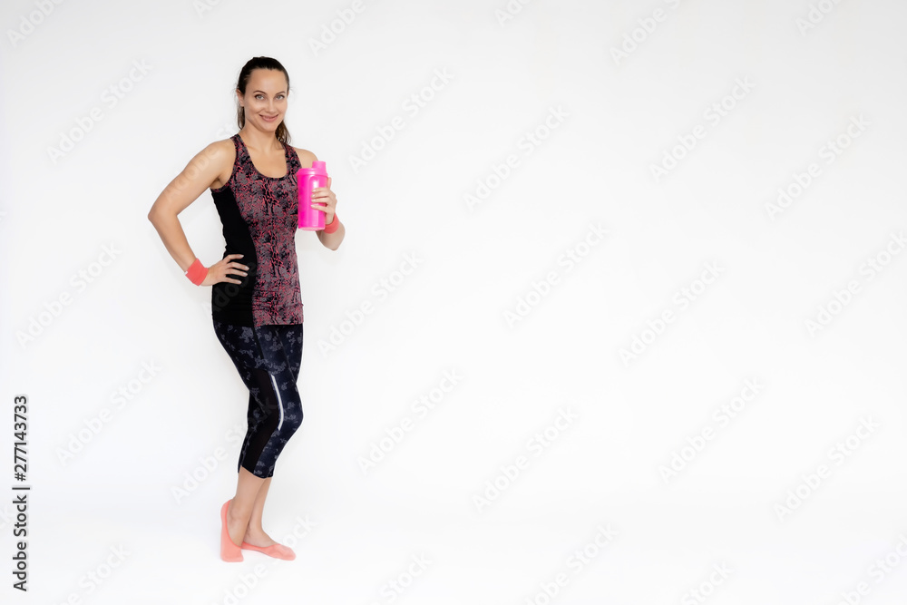 Full-length portrait on white background of beautiful pretty fitness girl woman in pink sports uniform, stands exercising in various poses with a shaker. Smiles Stylish trendy youth. Full-length portrait on white background of beautiful pretty fitness girl woman in pink sports uniform, stands exercising in various poses with a shaker. Smiles Stylish trendy youth.