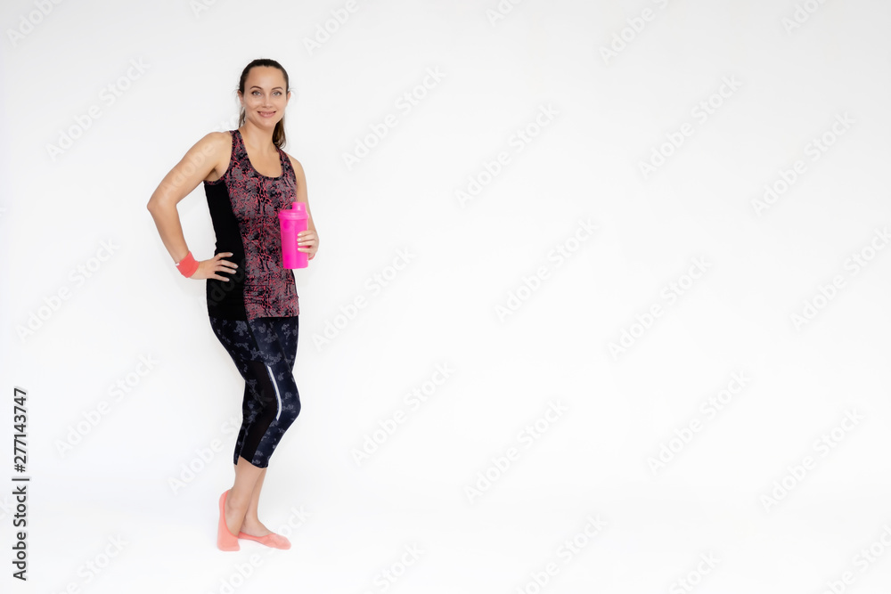 Full-length portrait on white background of beautiful pretty fitness girl woman in pink sports uniform, stands exercising in various poses with a shaker. Smiles Stylish trendy youth. Full-length portrait on white background of beautiful pretty fitness girl woman in pink sports uniform, stands exercising in various poses with a shaker. Smiles Stylish trendy youth.