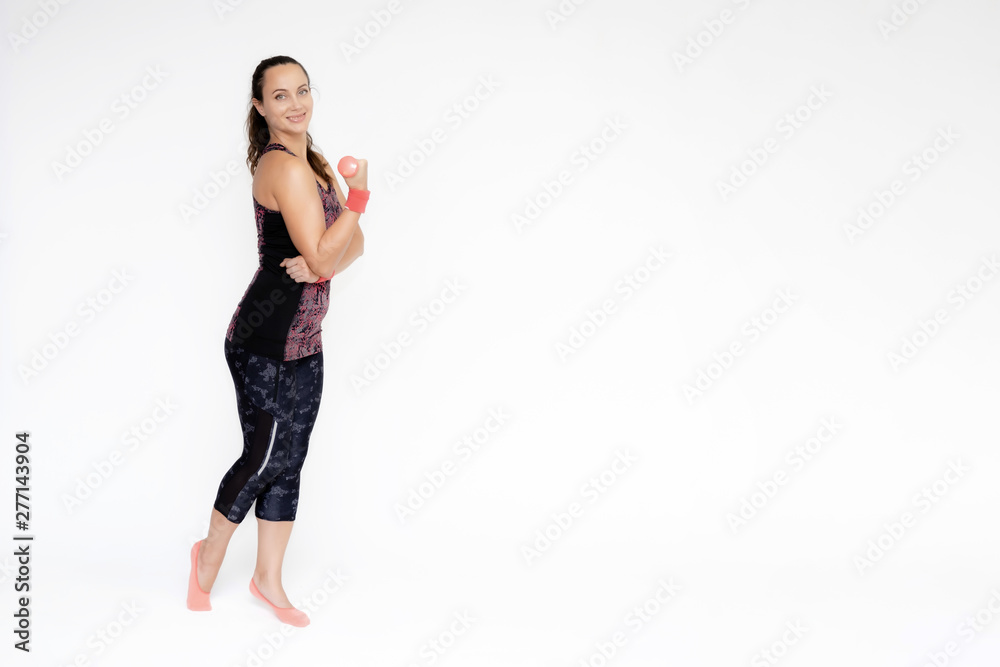 Full-length portrait on white background of beautiful pretty fitness woman girl in fashionable sportswear standing exercising in various poses with dumbbell. Smiles Stylish trendy youth. Full-length portrait on white background of beautiful pretty fitness woman girl in fashionable sportswear standing exercising in various poses with dumbbell. Smiles Stylish trendy youth.