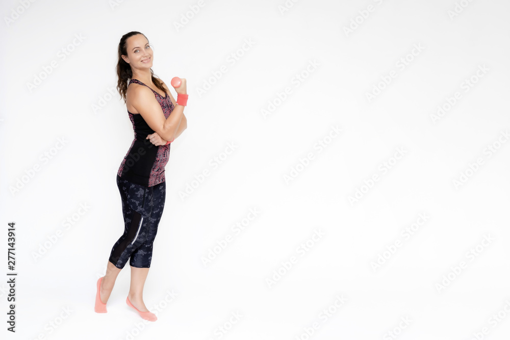 Full-length portrait on white background of beautiful pretty fitness woman girl in fashionable sportswear standing exercising in various poses with dumbbell. Smiles Stylish trendy youth. Full-length portrait on white background of beautiful pretty fitness woman girl in fashionable sportswear standing exercising in various poses with dumbbell. Smiles Stylish trendy youth.