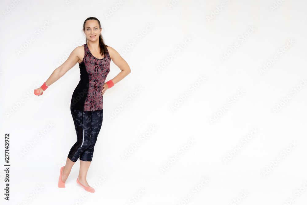 Full-length portrait on white background of beautiful pretty fitness woman girl in fashionable sportswear standing exercising in various poses with dumbbell. Smiles Stylish trendy youth. Full-length portrait on white background of beautiful pretty fitness woman girl in fashionable sportswear standing exercising in various poses with dumbbell. Smiles Stylish trendy youth.