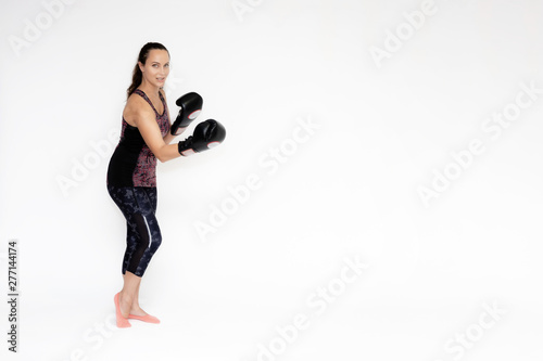 Full-length portrait on white background of beautiful pretty fitness woman girl in fashionable sportswear standing exercising in different poses with boxing gloves. Smiles Stylish trendy youth.