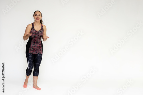 Full-length portrait on white background of beautiful pretty fitness woman girl in fashionable sportswear standing exercising in different poses, showing hands. Smiles Stylish trendy youth.