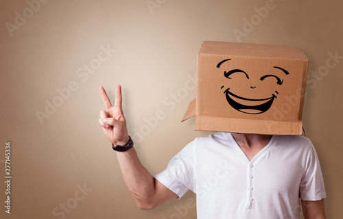 Young man with happy face illustrated cardboard box on his head