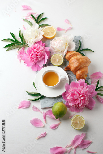 Cup of tea, citrus with fresh flowers peonies on white background. Holiday feminine breakfast, celebration morning concept. Top view. Copy space.