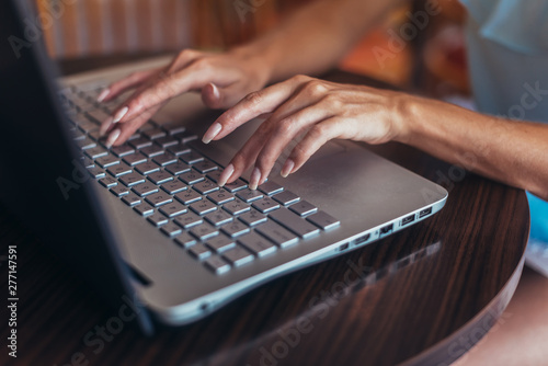 Close-up shot of female hands typing on laptop keyboard