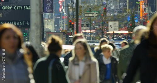 Massive Crowd of Tourists Walking In The Famous Streets Of New York With Busy Pedestrians Walking Past Big Lit Up Billboards And Iconic Yellow Traffic Lights Glowing Orange