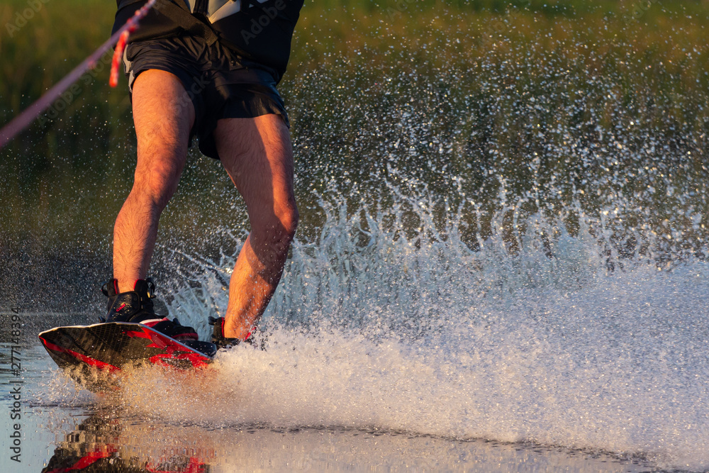 Men's feet on a wakeboard in water.guy on the river and is preparing to go wake boarding - obrazy, fototapety, plakaty 