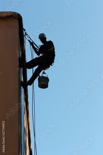 Industrial alpinism. The man is repairing the facade of the building.