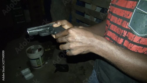 KINGSTON, JAMAICA : Jamaican young gang holding hand gun with bullet in dark alley at night.