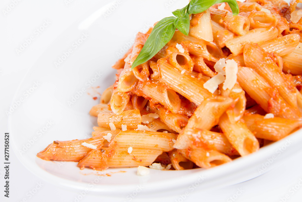 Penne with pesto rosso and sun dried tomatoes decorated with basil on a white background Penne with pesto rosso and sun dried tomatoes decorated with basil on a white background