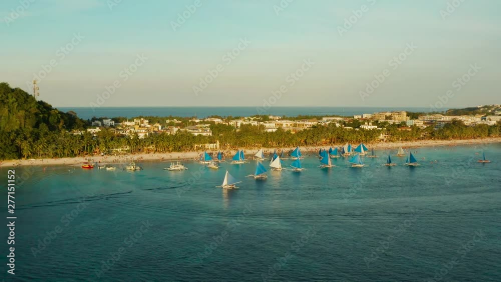 Tropical white beach from above at sunset with tourists and hotels and sailing boats on Boracay Island. Tropical white beach with sailing boat. Summer and travel vacation concept. Tropical white beach from above at sunset with tourists and hotels and sailing boats on Boracay Island. Tropical white beach with sailing boat. Summer and travel vacation concept.