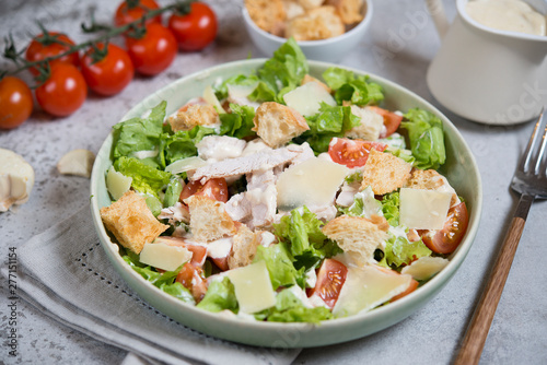Caesar salad with chicken, Parmesan and wheat croutons on a vintage grey background. Light diet dinner.
